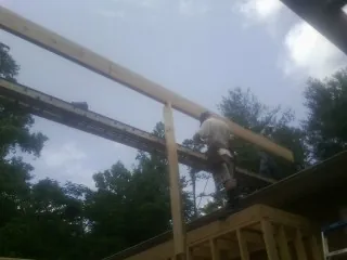 Carpenter setting a ridge beam over a new addition frame — Ice Dam Removal by Roofing Brothers in Blodgett