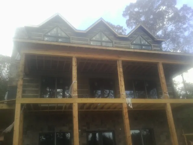 Dormers and porch framing on a large log home under construction — Roof Coating work by our crew in Blodgett