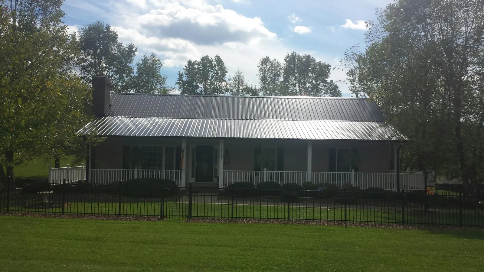Gray metal roof on a brick ranch with a full width front porch — Gutter Guard Installation work by our crew in Blodgett