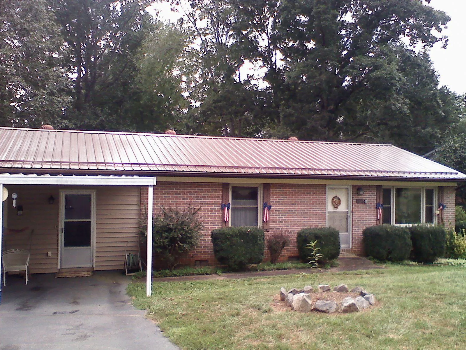 Bronze metal roof and carport on a brick ranch home — Roof Repair work by our crew in Blodgett